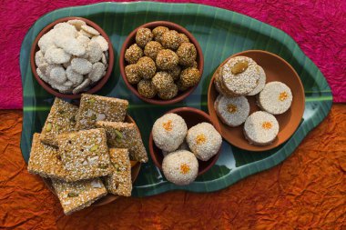 Makar sankranti special cuisine dish items Rewri, Tilgul, Til ke laddu, Chikki, Til baati all sweet items made with white sesame seeds and jaggery. Winter special indian food healthy seasonal