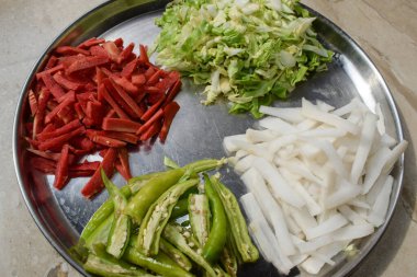 Köri veya salata tarifi hazırlamak için çelik tabakta taze çiğ sebzeler. Hindistan salatası kachumbar pişirme hazırlığı mutfakta.