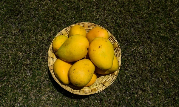 Arka planda bir sepette taze mango meyveleri..