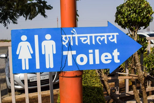 TOILET sign with Male and female icon. Rest room or bathroom signboard at public place outdoors with arrow howing direction. Written in big fonts in hindi Shauchalay