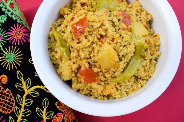 Traditional Indian fasting food recipe dish called Bhagar homemade of Barnyad millet rice grains. Also known as samo or sama pulao rice khichdi. Indian fasting food dish on red background