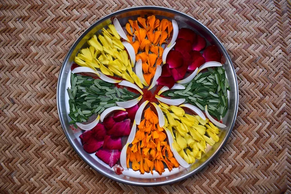 Aarti thali decoration. Hand made diy craft with flowers, flower petals of rosr, marigold, amla leaves. Thaali or plate decorated with flowers to make Pooja on Indian festivals. Flower rangoli making