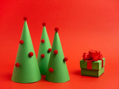 Yeni yıl kartı. Kağıttan, hediyeden ve parlak kırmızı arka planda karamel kamışdan yapılmış Noel ağacı..