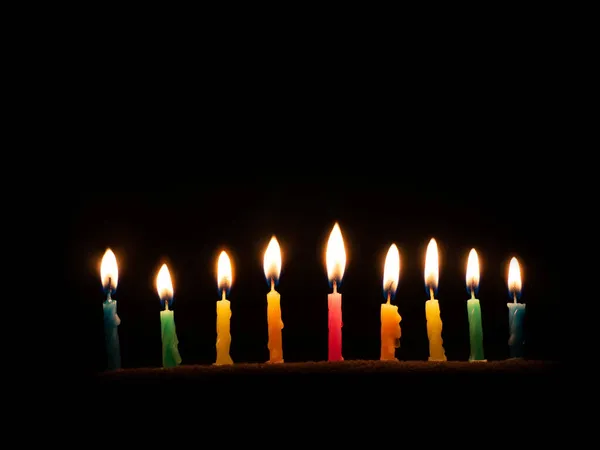 Chanukka ist ein jüdisch-religiöses Fest der Kerzen. Neun brennende Kerzen auf dunklem Grund. Das Fest des Feuers und Lichts Stockbild