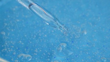 Pipetten küçük kabarcıklar damlayan temiz kozmetik jel damlaları. Yüz Serumu Yaşlanma Karşıtı Krem Hyaluronic Asit