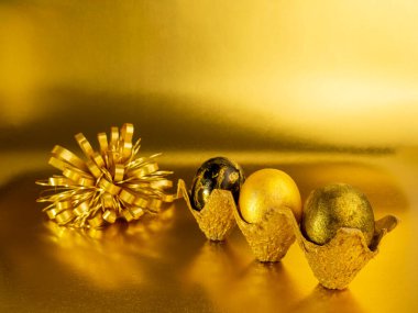 Paskalya altın yumurtalarının şık bir konsepti. Altın arka planda Paskalya altın yumurtaları. Kopyalama alanı olan kartpostal