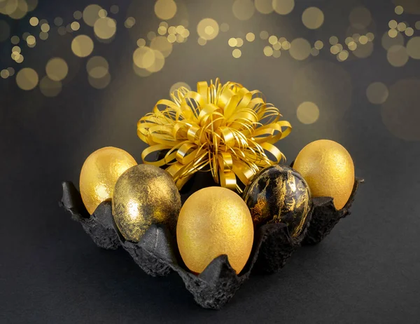 Stylish concept of Easter golden eggs. Easter golden eggs on a dark background with bokeh. Postcard with copy space — Stock Photo, Image