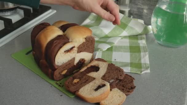 Frauenhände schneiden ein Stück Brot aus weißem und Schokoladenteig mit Schokolade darin — Stockvideo