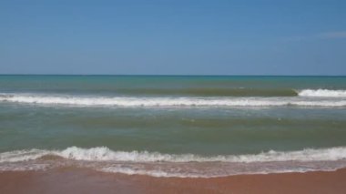 Deniz dalgaları kumlu sahilde yuvarlanıyor. Eğlence, seyahat ve turizm kavramı