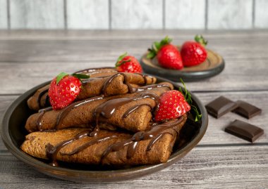 Çikolata hamurundan yapılmış gözlemeler çilekli, çikolatalı. Maslenitsa, lezzetli bir tatlı..