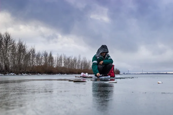 donmuş bir göl kenarında balıkçı
