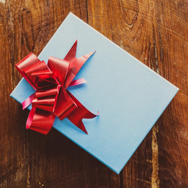 Синя подарункова коробка з червоною стрічкою на дереві для вінтажу — стокове фото