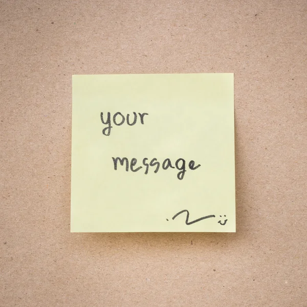 Yellow sticky note message on brown paper texture close up — Stock Photo, Image