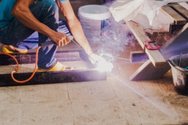 Kaynak makinesi kullanarak bir konut binasında metal merdiven yapısı yapan bir kaynakçı..