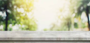 Boş beton masa üstü ve soyut bulanık ışık hüzmesi ve gün ışığında bahçe ağaçlarının bulanık arkaplanı. kopyalama alanı olan ürün görüntüleme şablonu.