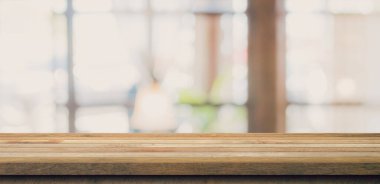 Kahvehanedeki bulanık insanlarla ahşap masa üstü ve ekran montajı için kafe arka planı, kopyalama alanı.