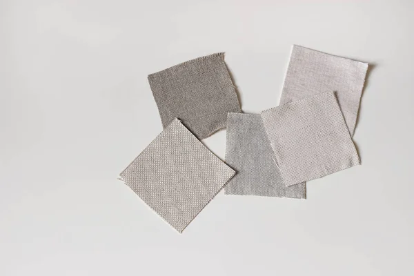 Fabric samples. Linen, cotton and velevt textile swatches isolated on white table backgound. Flat lay, top view. Neutral color palette mood board. Renovating, upholstery remodeling craft concept.