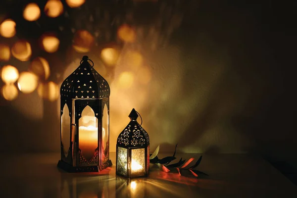Lanternas árabes decorativas com velas acesas à noite. Luzes douradas brilhantes de bokeh. Cartão festivo, convite. Mês sagrado muçulmano Ramadã Kareem. Fundo escuro com ramo de oliva. — Fotografia de Stock