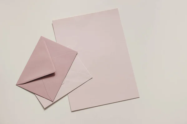 Set of pastel, blush pink blank envelopes and paper sheet mockups. Beige neutral background. Mailing, correspondence and post concept. Business, office stationery still life. Flat lay, top view. — Fotografia de Stock