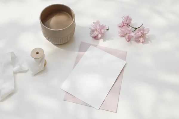 शादी की संरचना। स्त्री वसंत नाश्ता अभी भी जीवन। गुलाबी जापानी चेरी पेड़, साकुरा सूरज की रोशनी में फूल। खाली ग्रीटिंग कार्ड, निमंत्रण। कॉफी का कप। सफेद डैपल्ड टेबल पृष्ठभूमि . — स्टॉक फ़ोटो, इमेज