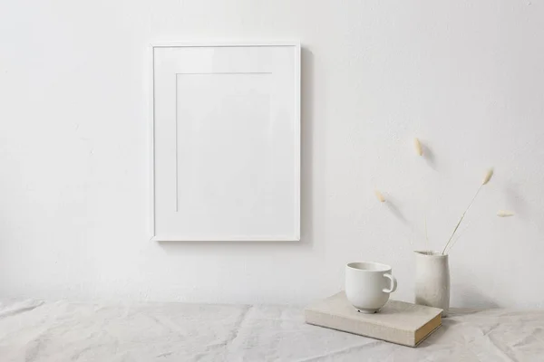 Neutral breakfast still life scene. White wooden picture frame mockup. Vase with dry lagurus bunny tail grass. Cup of coffee on book. Linen table cloth, white wall. Scandinavian interior. Boho style. — Stock fotografie