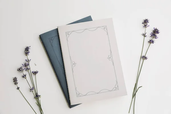 Summer lifestyle floral composition.Blue and grey diary cover, book mockups scene with lavender flowers in sunlight. beige table background, flat lay, top view. Summer, French or spa concept.