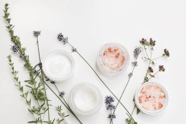 Organic beauty cosmetics still life, web banner. Skin cream, moisturizer and pink Himalayan salt isolated on white table background. Lavender, oregano and satureja herbs. Spa concept, flat lay, top