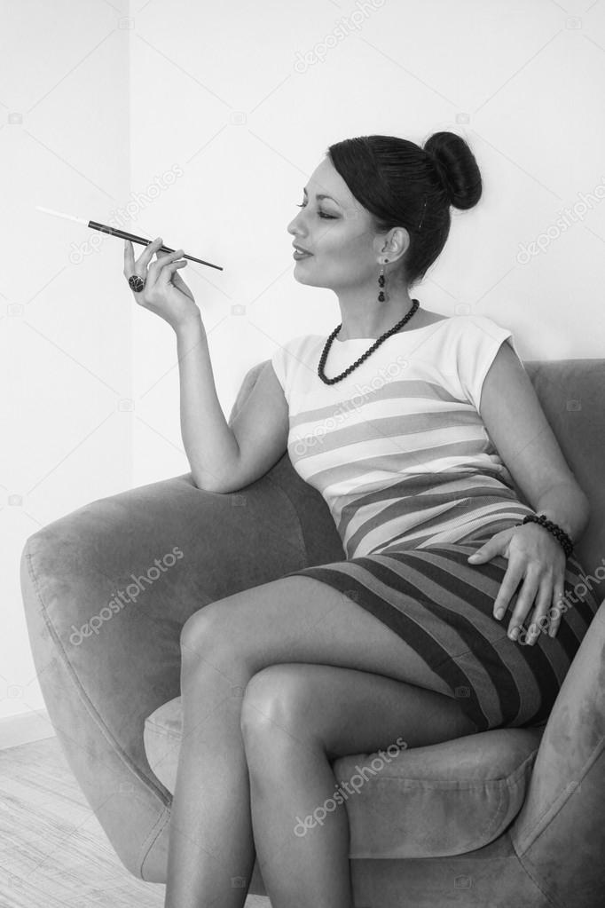 Young woman dressed in retro style with cigarette sitting in an