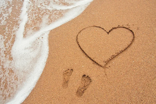 Forma del cuore e impronte nella sabbia sulla spiaggia — Foto Stock