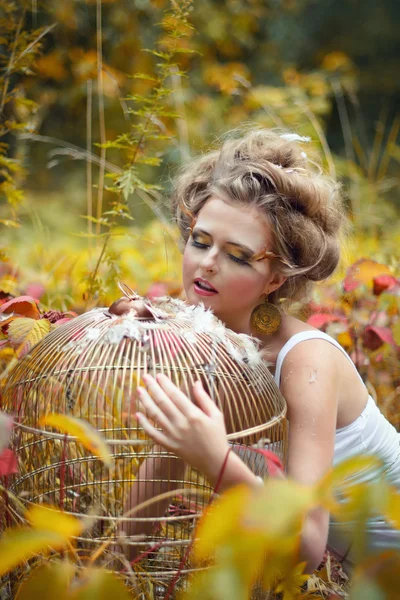 Gyönyörű tündér lány arany kalitkával az erdőben — Stock Fotó