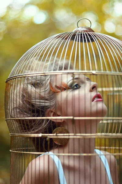 Menina loira bonita em uma gaiola dourada — Fotografia de Stock