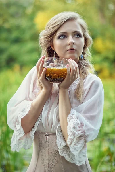 Schönes Mädchen mit einer Tasse grünem Tee in der Hand auf grünem Bac — Stockfoto