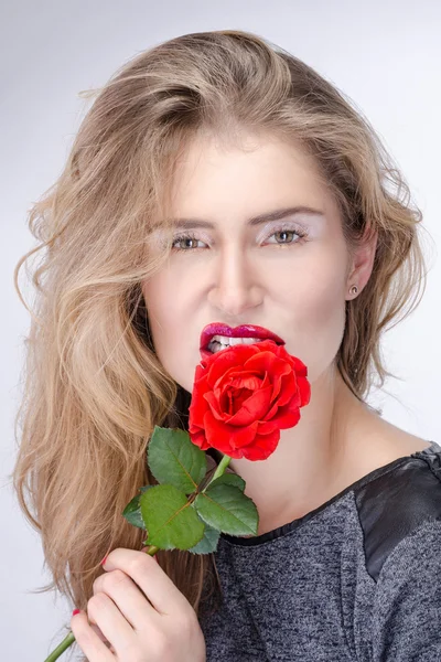 Pretty blond girl with bright makeup biting a flower — Stock Photo, Image
