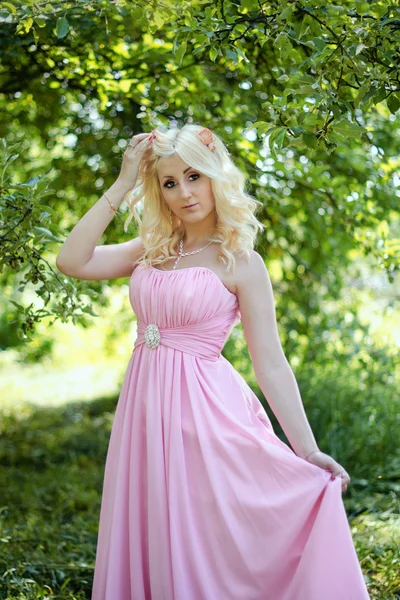 Docela blondýnka v růžových šatech v parku — Stock fotografie