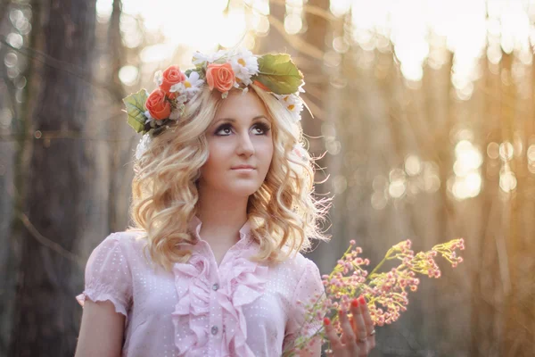 Pretty blonde girl in a pink dress and with flower wreath in the — Stock Photo, Image