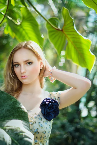 Vacker blond flicka bland palmblad — Stockfoto