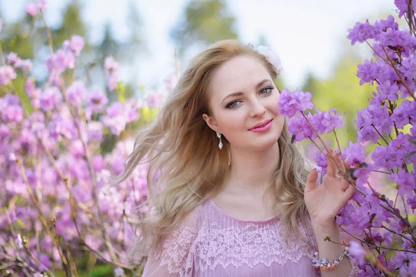 Vacker blond flicka bland våren blommande grenar — Stockfoto