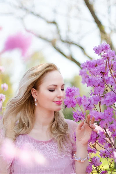 Vacker blond kvinna bland våren blommande grenar — Stockfoto