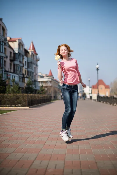 Cheerful girl jumping with lollipop — Stock Photo, Image