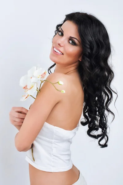 Vackra mörka haired girl med orkidéer på vit bakgrund — Stockfoto