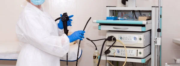 Доктор гастроэнтеролог в защитной одежде держит эндоскоп перед гастроскопией. Медицинское обследование, медицинская посуда и инструменты, эндоскопия желудочно-кишечного тракта в современной больнице. — стоковое фото