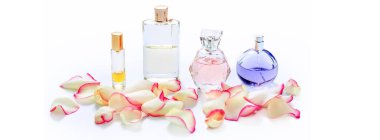 Arka planda çiçek yaprakları olan parfüm şişeleri. Parfüm, parfüm koleksiyonu. Kadın aksesuarları.