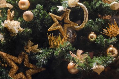Altın yıldızlar ve taçlarla süslenmiş Noel ağacı.
