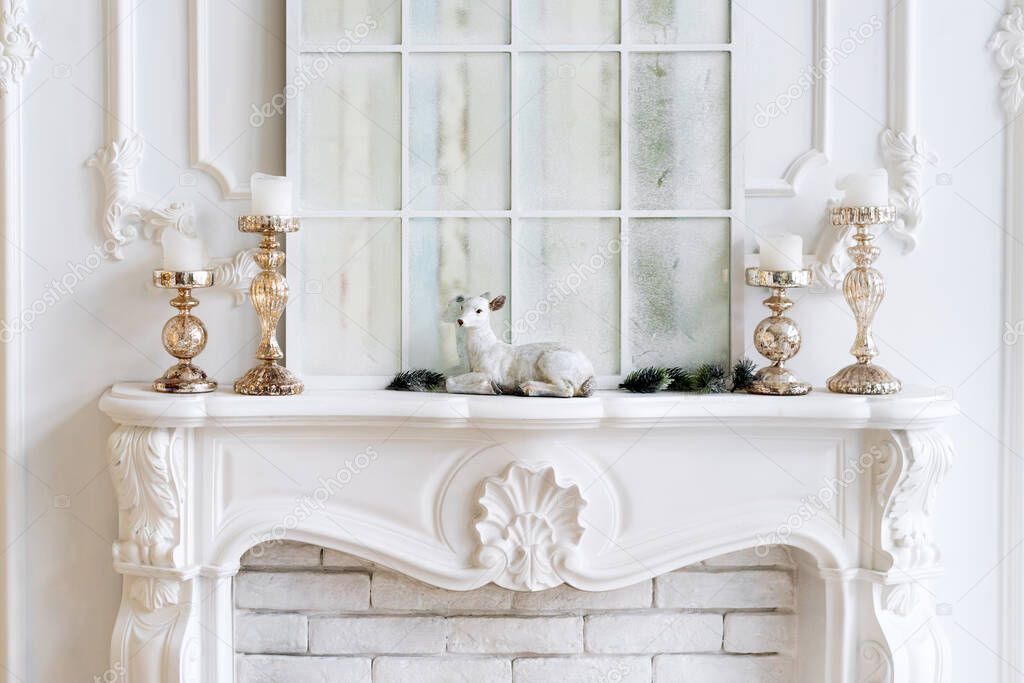 White mantelpiece with candles and christmas decorations. Classic interior.