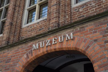 Kırmızı tuğla duvarda tek kelime MUZEUM. Polonya 'nın Torun kentindeki müze binasının müzesine imza atın.