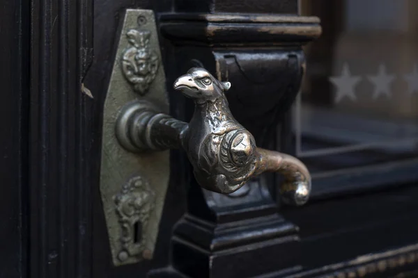 Stará klika. Dřevěné vchodové dveře se starožitnými klikami ve tvaru ptáka. Selektivní zaměření — Stock fotografie