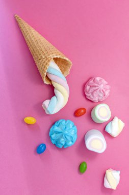 Pembe arka planda waffle külahlı şekerleme. Şeker, şeker, şeker, lokum ve dondurma külahı. Bedava kopyalama alanı, pastel renkler