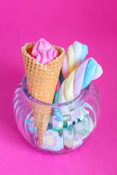 ピンクの背景にガラス瓶にワッフルコーンとキャンディとマシュマロ スイーツ キャンディー マシュマロ アイスクリームコーン フリーコピースペース パステルカラー — ストック写真