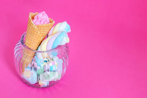 ピンクの背景にガラス瓶にワッフルコーンとキャンディとマシュマロ スイーツ キャンディー マシュマロ アイスクリームコーン フリーコピースペース パステルカラー — ストック写真