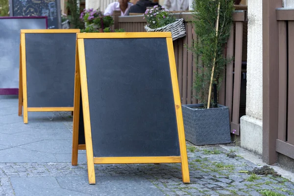 Blank restaurant shop sign or menu boards near the entrance to restaurant. Cafe menu on the street. Blackboard sign mockup in front of a restaurant. Signboard, freestanding A-frame blackboard.